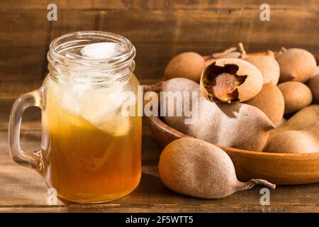 Tamarindensaft in einem Glas, umgeben von frischen reifen Tamarinden - Tamarindus indica Stockfoto