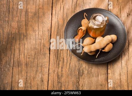 Tamarindensaft in einem Glas, umgeben von frischen reifen Tamarinden - Tamarindus indica Stockfoto
