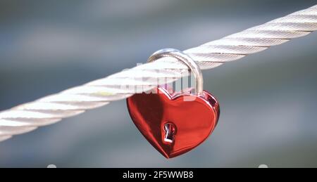 Rote Liebe Schloss an einen Zaun in der Form eines Herzens Stockfoto