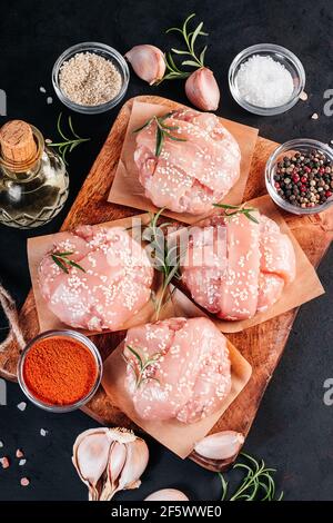 Nahaufnahme von oben von vier Hähnchenburgern mit Rosmarinzweig mit verschiedenen Gewürzen zum Kochen auf schwarzem Hintergrund. Fast Food. Konv Stockfoto