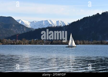Tegernsee, Deutschland. März 2021, 28th. Ein Segelboot gleitet über den Tegernsee in den bayerischen Alpen. Sonnenschein und frühlingshafte Temperaturen zogen viele Tagesausflügler am Sonntag an den See. Quelle: Katrin Requadt/dpa/Alamy Live News Stockfoto