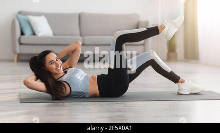 Athletische junge Frau, die zu Hause trainiert, knirscht Stockfoto