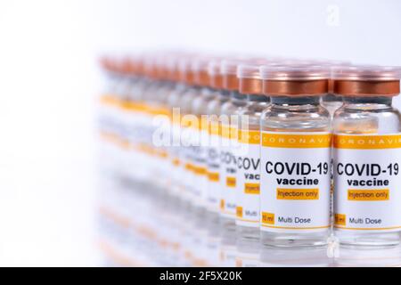 Zwei Reihen von Fläschchen mit Coronavirus-Impfstoff auf weißem Tisch mit Reflexionen. Labor- oder Gesundheitseinrichtung Konzept Stockfoto