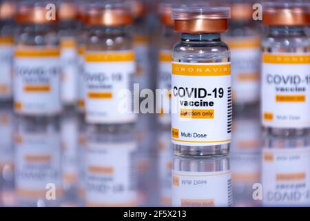 Coronavirus-Impffläschchen auf einem weißen Tisch mit Reflexionen. Labor- oder Gesundheitseinrichtung Konzept Stockfoto