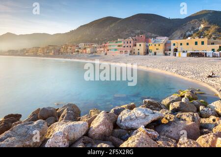 Nebliger Sonnenuntergang über den bunten Häusern und dem Strand von Varigotti, Finale Ligure, Bezirk Savona, Ponente Riviera, Ligurien, Italien. Stockfoto