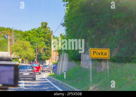 Gelbes Ortsschild und Straße nach Postojna Pivka in Slowenien. Stockfoto