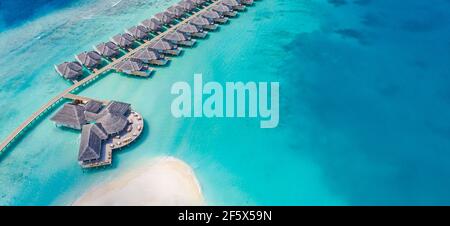 Luftaufnahme der Malediven Insel, Luxus Wasservillen Resort und hölzernen Pier. Wunderschöner Himmel und Ozean Lagune Strand Hintergrund. Sommerurlaub Stockfoto