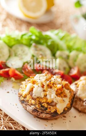 Mediterrane Küche. Gefüllte Pilze mit Käse, Salat, Tomaten, Gurken, Zitrone. Stockfoto