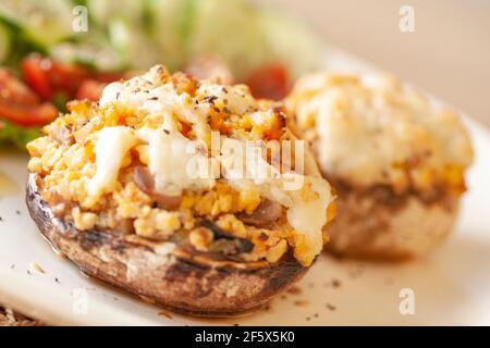 Mediterrane Küche. Gefüllte Pilze mit Käse, Salat, Tomaten, Gurken, Zitrone. Stockfoto