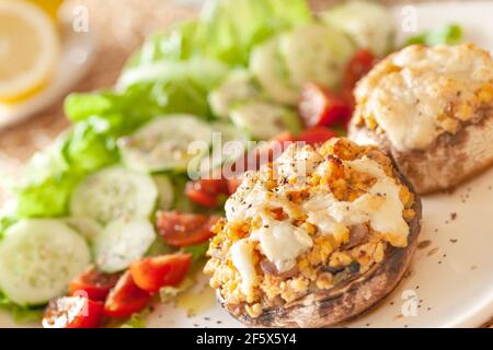 Mediterrane Küche. Gefüllte Pilze mit Käse, Salat, Tomaten, Gurken, Zitrone. Stockfoto