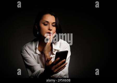 Low-Key-Porträt der schönen Frau mit Handy spät in der Nacht schlaflos im Dunkeln mit Smartphone und Internet. Stockfoto