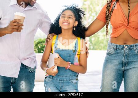 Kleines Mädchen, das mit ihren Eltern zur Schule geht. Stockfoto