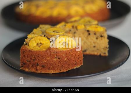 Scheiben von hausgemachtem Kochbananen-Kuchen mit Kochbananen als Belag. Aufgenommen auf weißem Hintergrund. Stockfoto