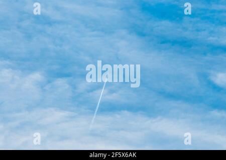 Spur eines fliegenden Flugzeuges am blauen Himmel mit weichen weißen flauschigen Wolken Hintergrund. Stockfoto