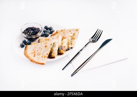 Pfannkuchen auf weißem Teller mit Besteck. Pfannkuchen Dessert.Crepes mit Schokoladencreme. Stockfoto
