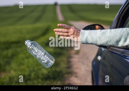 Wegwerfen Plastikflasche aus dem Auto. Fahrer wirft Müll auf der Straße. Umweltschutz Stockfoto