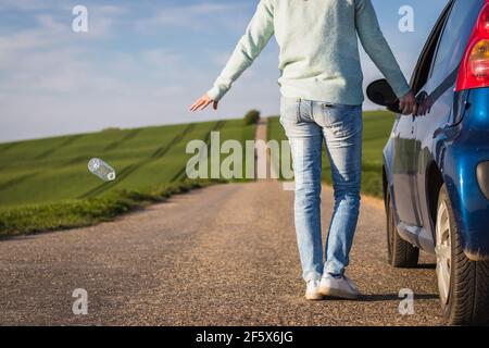 Fahrer wirft Plastikflasche auf der Straße. Plastikverschmutzung in der Natur. Stockfoto