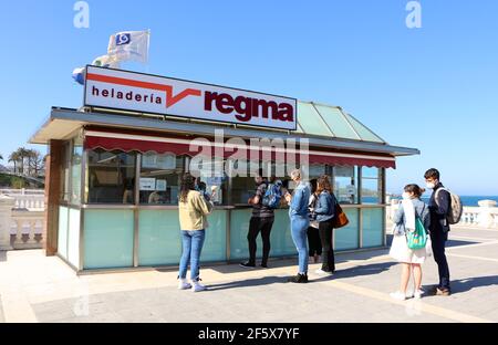 An einem windigen, sonnigen Frühling stehen junge Menschen in der Schlange, um Eis zu essen. Palmsonntag Sardinero Santander Cantabria Spanien Stockfoto