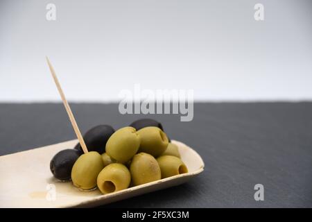 Grüne und schwarze Oliven in einer Bambusschüssel Stockfoto