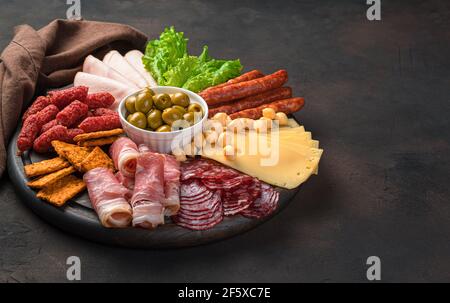 Wurst- und Käseschneiden auf einem runden Schneidebrett auf braunem Hintergrund. Seitenansicht mit Kopierbereich. Stockfoto