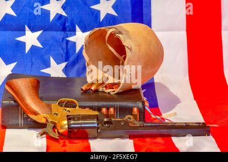 Die Heilige Bibel, Bulle Hodensack, Kugeln und Revolver auf der amerikanischen Flagge Stockfoto
