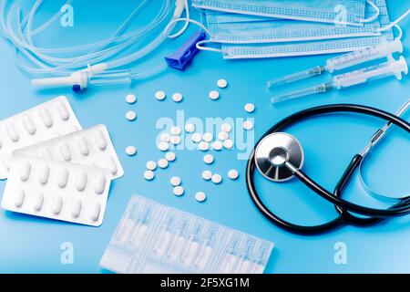 Stethoskop auf blauem Hintergrund mit Pillen, medizinischen Ampullen, Tropf und Spritzen für Injektionen. Gesundheitskonzept. Medizinische Eigenschaften eines Arztes. Stockfoto