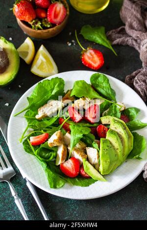 Gesunde Ernährung, Ernährung Mittagessen Menü Konzept, ketogene Ernährung und Paläodiät. Sommersalat mit Erdbeeren, gegrilltem Hähnchen und Avocado auf einem Steintisch. Stockfoto