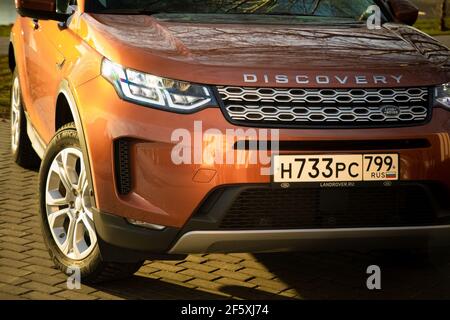 Moskau, Russland - 20. Dezember 2019: Der neue Land Rover Discovery Sport 2019 steht auf dem Park. Nahaufnahme der Vorderansicht der Seite. Scheinwerfer, Stoßfänger und Haube von orange suv, silberne Räder, .. Stockfoto