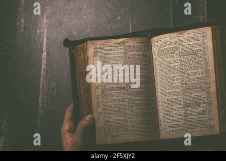 Gebet, Mann übergibt ein altes offenes Buch Heilige Bibel, Holzschreibtisch Hintergrund. Stockfoto