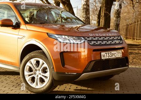 Moskau, Russland - 20. Dezember 2019: Der neue Land Rover Discovery Sport 2019 steht auf dem Park. Nahaufnahme der Vorderansicht der Seite. Scheinwerfer, Stoßfänger und Haube von orange suv, silberne Räder, .. Stockfoto