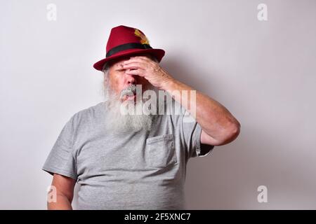 Ein schockierter amerikanischer Rüde mit grauem Hemd und Rot fedora Hut auf weißem Hintergrund Stockfoto