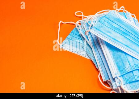 Eine Nahaufnahme eines Stapels neuer unbenutzter medizinischer Medikamente Schützende hygienische Gesichtsmasken isoliert auf einem orangen Hintergrund Stockfoto