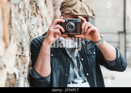 Junger Hipster-Mann, der mit einer alten Retro-Kamera fotografiert. Stockfoto