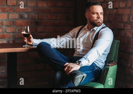 Schöner junger Mann, der ein Glas Rotwein genießt Stockfoto