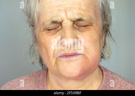 Depressive reife Frau isoliert auf grauem Studio Hintergrund berühren Wange leiden unter Zahnschmerzen Stockfoto