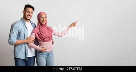 Schau Mal. Happy Middle Eastern Family Zeigt Beiseite Auf Copy Space Stockfoto