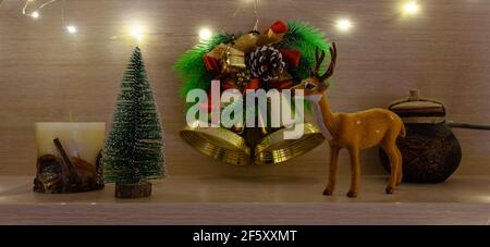 Weihnachtsglocken, Hirsche und Weihnachtsbaum auf einem Holzregal Stockfoto