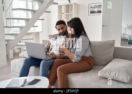 Junge indische Paar Überprüfung Rechnungen Zahlung Schulden online mit Laptop zu Hause. Stockfoto