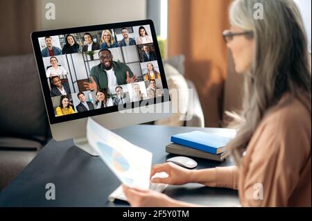 Erfolgreiche, selbstbewusste, schöne, reife, grauhaarige Asiatin mit Brille, Geschäftsfrau, ceo, Manager, Chat bei Telefonkonferenz, Online-Meeting mit einem gemischtrassig-Business-Team Stockfoto