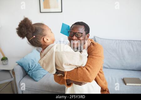 Portrait von glücklichen afroamerikanischen Vater umarmt Tochter nach Hause kommen von der Arbeit am Vatertag, kopieren Raum Stockfoto