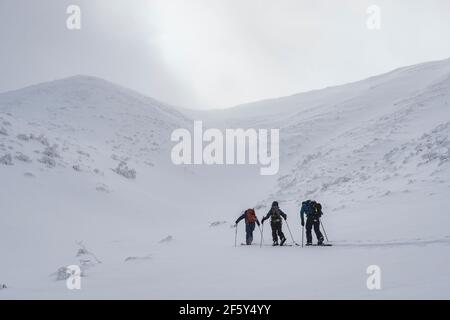 Rückansicht von Menschen mit Rucksäcken und Skistöcken Splitboarding Auf schneebedeckten Berg gegen Himmel Stockfoto