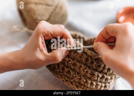 Nahaufnahme von Frauenhänden, die aus Jute stricken Stockfoto
