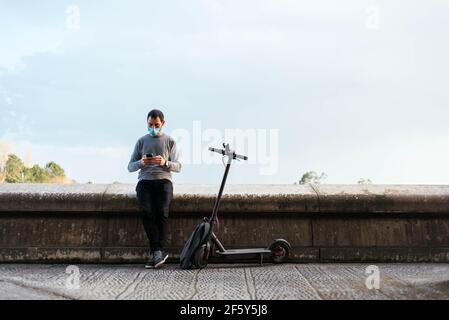 Mann mit Smartphone in der Nähe Elektroroller Stockfoto