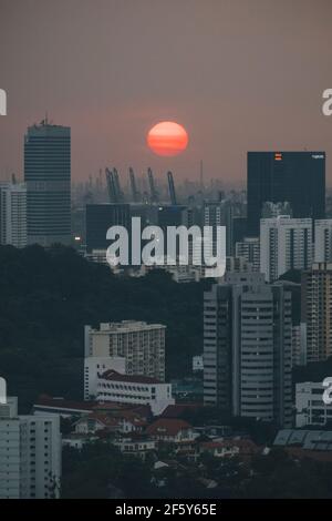 Sonnenuntergang hinter Singapurs hohen Gebäuden Stadtbild gegen bewölkten Himmel bei Sonnenuntergang. Stockfoto