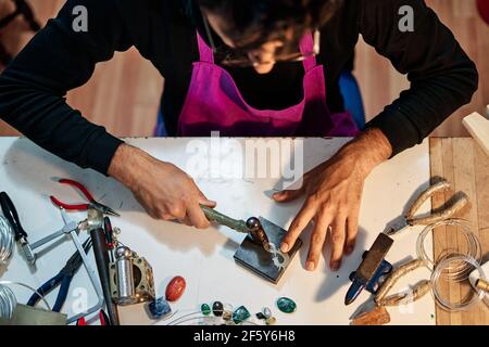 Foto des Kunsthandwerker Juweliers, der das Schmuckstück auf dem arbeitet Arbeitstisch Stockfoto