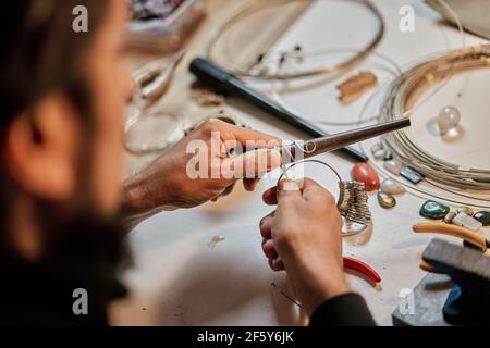 Nahaufnahme der Hände des Kunsthandwerkers Juwelier arbeiten an der Arbeitstisch in der Werkstatt Stockfoto