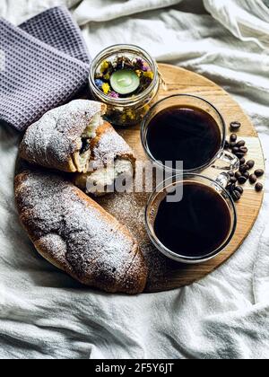 Kaffee und Croissants auf einem runden Holzbrett Stockfoto