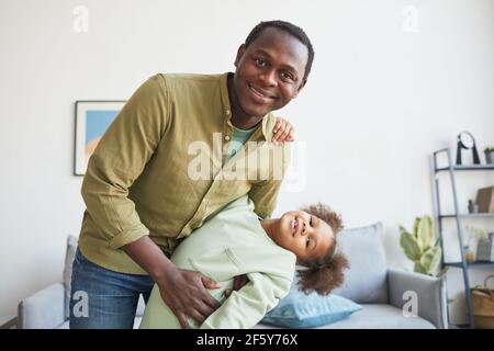 Porträt eines glücklichen afroamerikanischen Vaters, der mit seiner Tochter zu Hause spielt und die Kamera anlächelt, den Kopierraum Stockfoto
