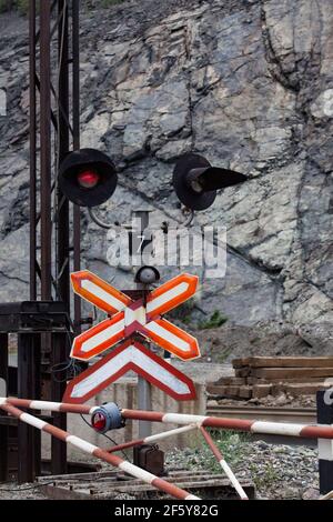 Tagebau-Eisenerz. Im Steinbruch mit der Bahn abfahren. Straßenschild und rote Stoppleuchte an der Kreuzung. Gesteine von Mineralien auf dem Hintergrund. Stockfoto