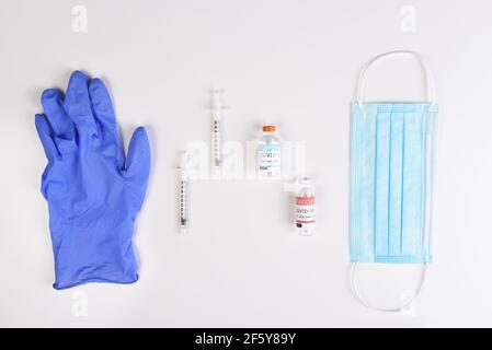 Ausrüstung zur Verabreichung einer Covid19-Impfung. Flach legen mit OP-Maske, Spritzen, Impfstofffläschchen und Handschuh.
